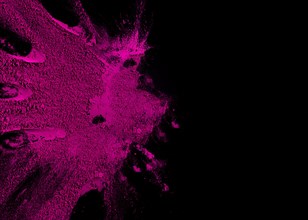Overhead view pink color powder explosion with copy space text black surface