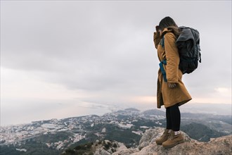 Young woman with her backpack standing top mountain looking idyllic view