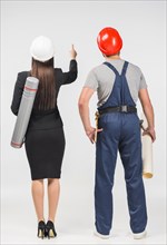 Woman engineer standing with builder pointing up
