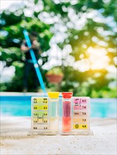 Pool water PH tester kit on the edge of the swimming pool. Tester kit to measure chlorine and ph in swimming pools