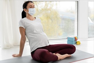 Pregnant woman with medical mask relaxing