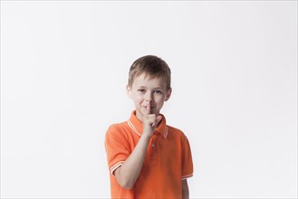 Smiling boy with finger lips making silent gesture
