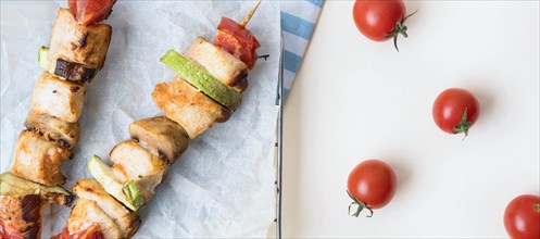 Top view chicken skewers parchment paper with tomatoes
