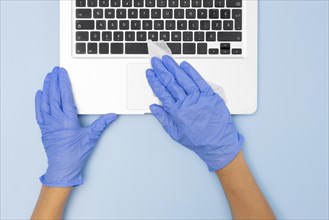 Top view hands with surgical gloves disinfecting laptop