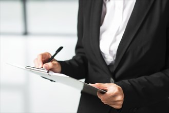 Businesswoman writing clipboard with black pen