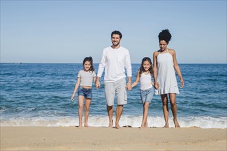 Happy family posing holding hands