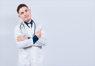 Smiling latin doctor pointing finger at a space isolated. Young doctor showing at a blank space. Doctor pointing at an isolated white space