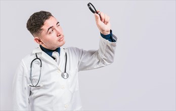 Doctor looking for something with magnifying glass looking isolated. Handsome Doctor holding magnifying glass and looking for something