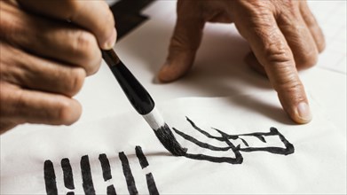 Close up man writing chinese symbols white paper