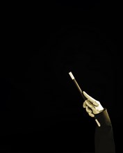 Magician s hand holding magic wand against black background