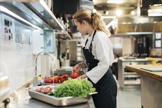 Side view female chef washing vegetables kitchen