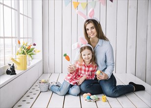 Cute girl mother bunny ears sitting with easter eggs