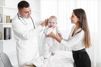 Mother holding baby while doctor looking it