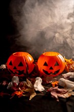 Halloween pumpkins over autumn leaves and ghosts with smoke on a black background