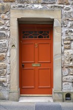 Red front door on an old stone house