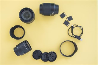Professional digital camera accessories arranged circle yellow background
