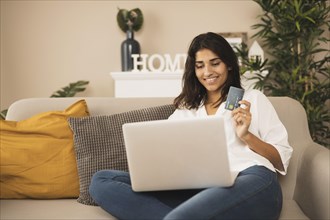 Smiling woman working laptop holding credit card