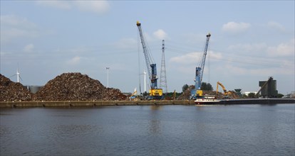 Dock cranes and heaps of scrap metal at Van Heyghen Recycling export terminal in the port of Ghent