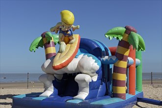 Inflatable bouncy castle with cartoon character Surfer on the beach