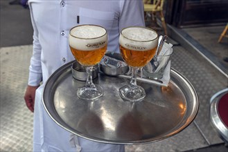 Waiter brings two beers on a tray