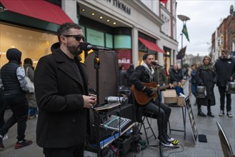Andrew Kavanagh of Irish group Keywest singing in Grafton street with Andrew Glover in the back ground. Dublin