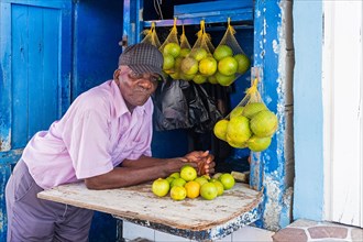 Old local black man selling oranges and lemons at market in the city Georgetown