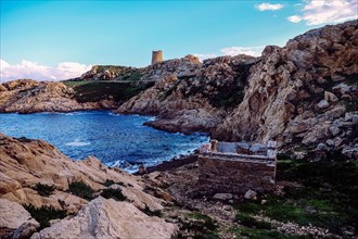 Historic watchtower from the time of the Genoese occupation and dilapidated beach house on the Mediterranean island of Corsica
