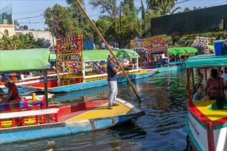 Popular tourist attraction people boating on colourful barges on canal at Xochimiloco