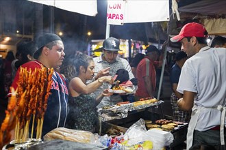 Mexicans buying grilled meat at food stall at the night market along the Malecon