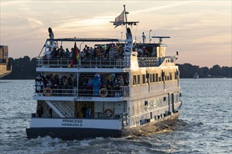 Party guests on the excursion ship MS Princess at dusk underway on the Elbe in Hamburg harbour