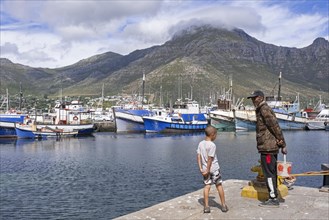 Elderly black man and boy watching fishing boats in the port