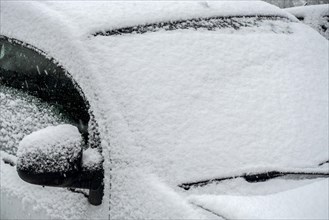 Parked car covered in snow during unexpected late snow shower in March 2023