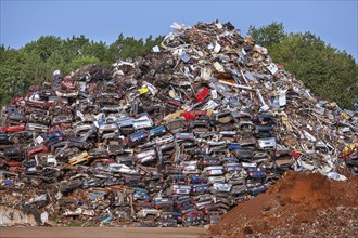 Cars piled up for recycling into scrap metal at junkyard
