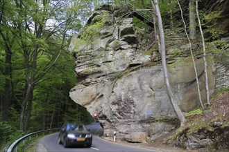 Car driving under the sandstone rock formation Predigtstuhl in Berdorf