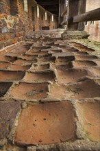 Worn-out red bricks in corridor and inner court of the medieval Beersel Castle