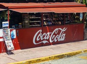 View from bus window of street snack shop labelled with Coca-Cola branding