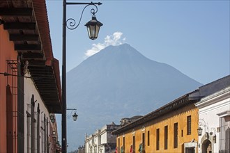 Volcan de Fuego volcana and colourful colonial houses in the city Antigua Guatemala