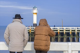Elderly couple dressed in warm coats on the wooden pier at the Nieuwpoort