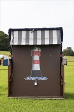 Beach chair with lighthouse painting on a green meadow at the beach of Cuxhaven
