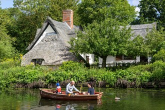 Rowing boat passing thatched Bridge Cottage
