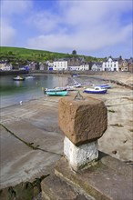 Old stone with sundial and sailing boats at low tide in the picturesque harbour of Stonehaven