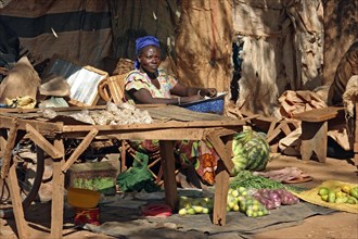 Black woman selling fruit and vegetables at market stall in Kongoussi