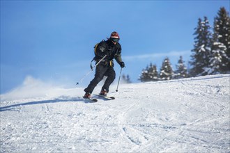 Skier skiing down ski slope in winter sports resort in the Alps