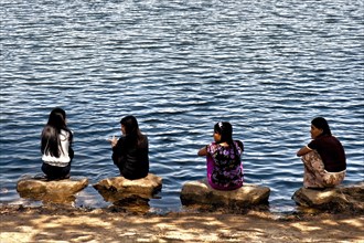 Women squatting on stones by the lake