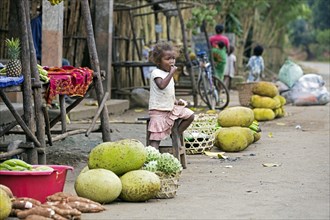 Little Malagasy girl at roadside market stall selling durian