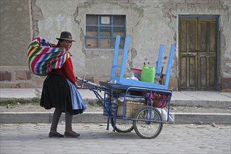 Traditional dressed Bolivian woman with pushcart going to market in Challapata
