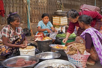 Burmese women selling food on the ground at market in Yangon