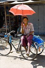 Rickshaw driver with red umbrella waiting at the market