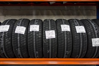 Row of new summer tires on shelves stored in tire centre
