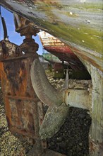 Rusty screw propeller and rudder from wooden wreck of trawler fishing boat in the harbour of Camaret-sur-Mer